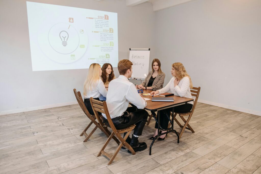 Group of professionals engaged in a meeting in a bright conference room with presentation screen.
